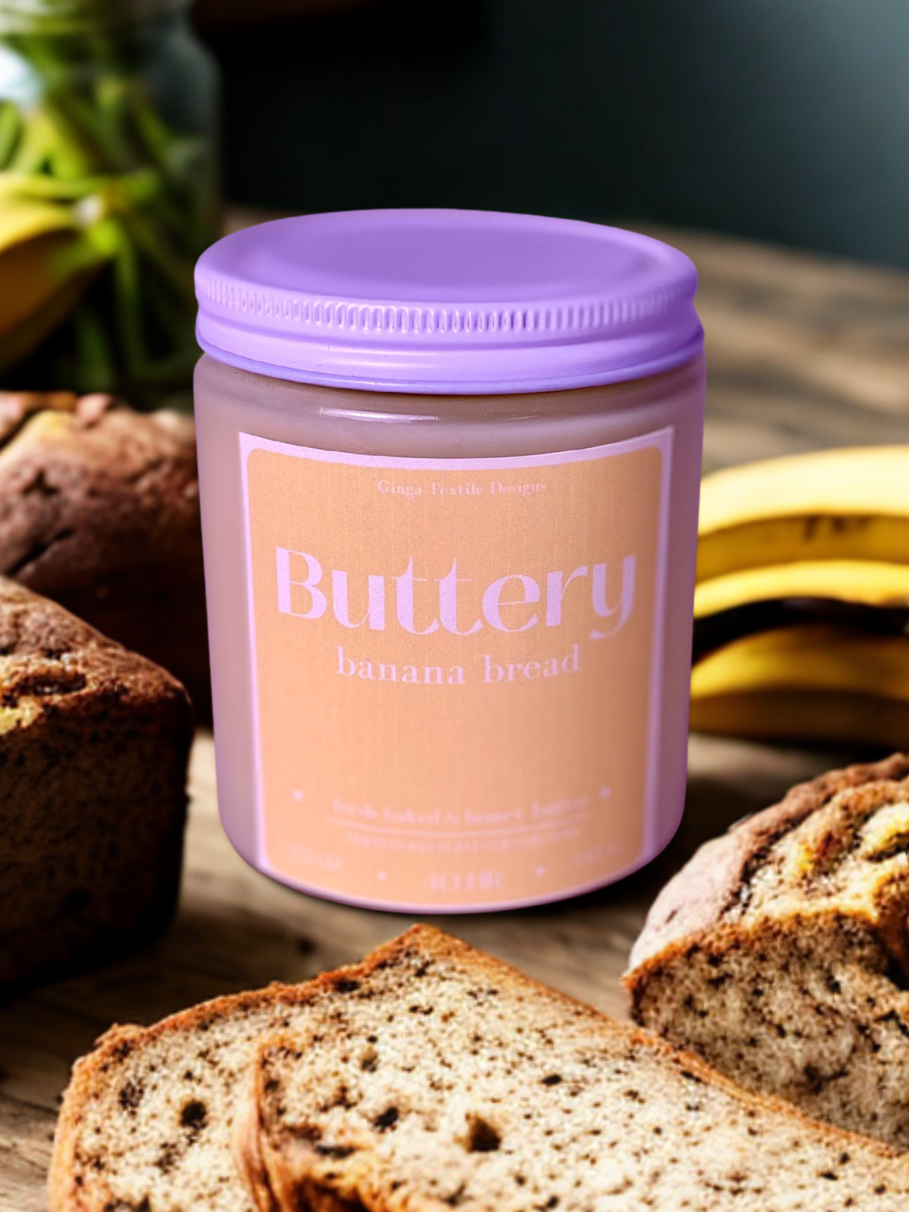 Jar of 'Buttery Banana Bread' scented candle with slices of banana bread and bananas in the background