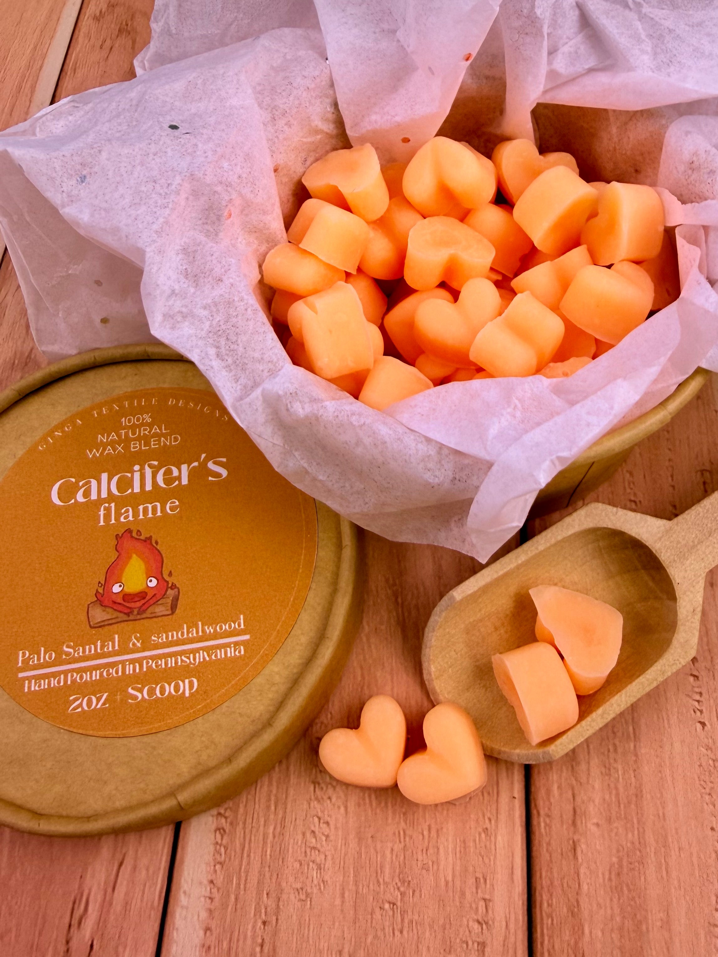 Calcifer's Flame wax melts cubes in a wooden scoop on a wooden surface