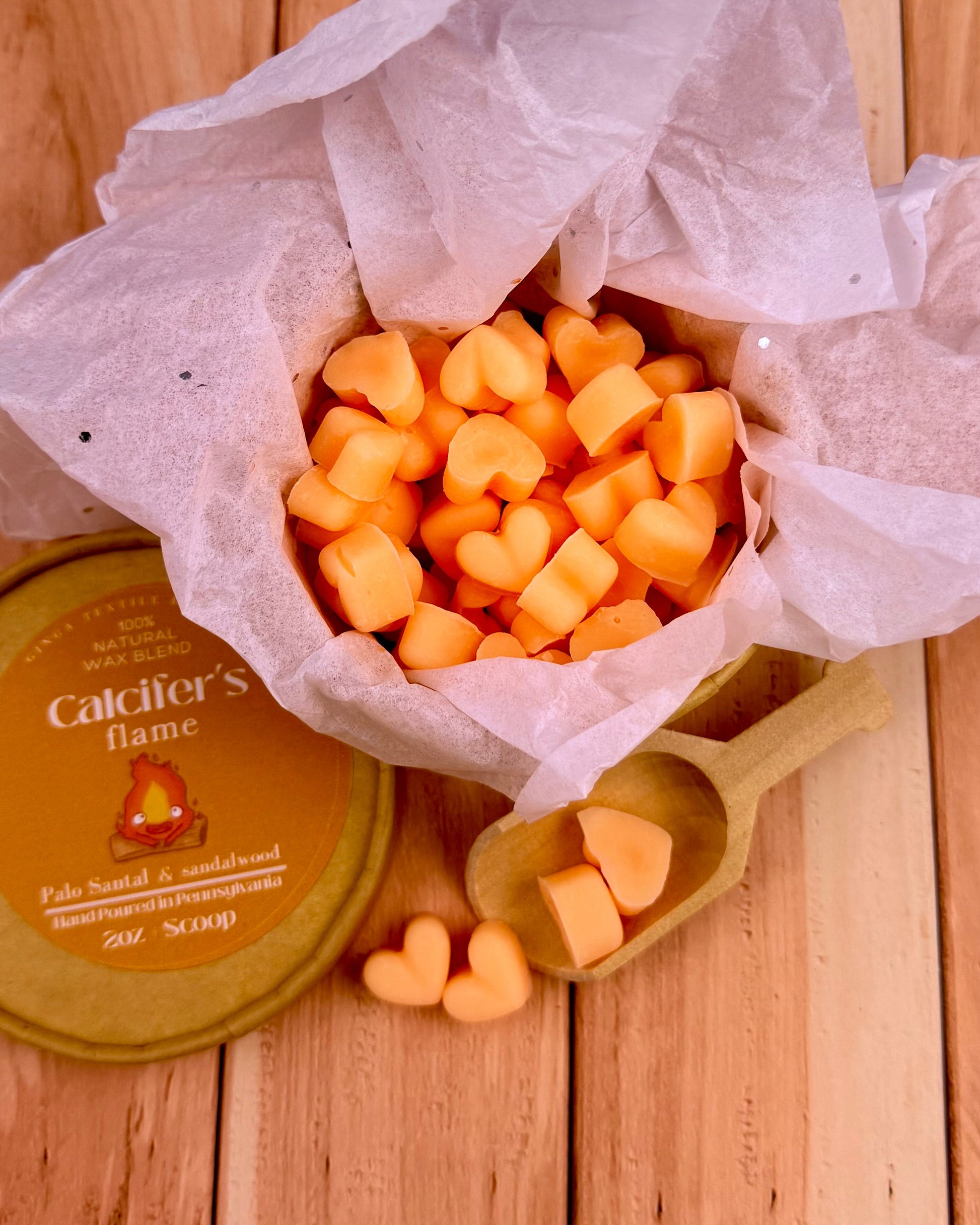 Heart-shaped wax melts in a container with Calcifer's Flame branding on a wooden surface.