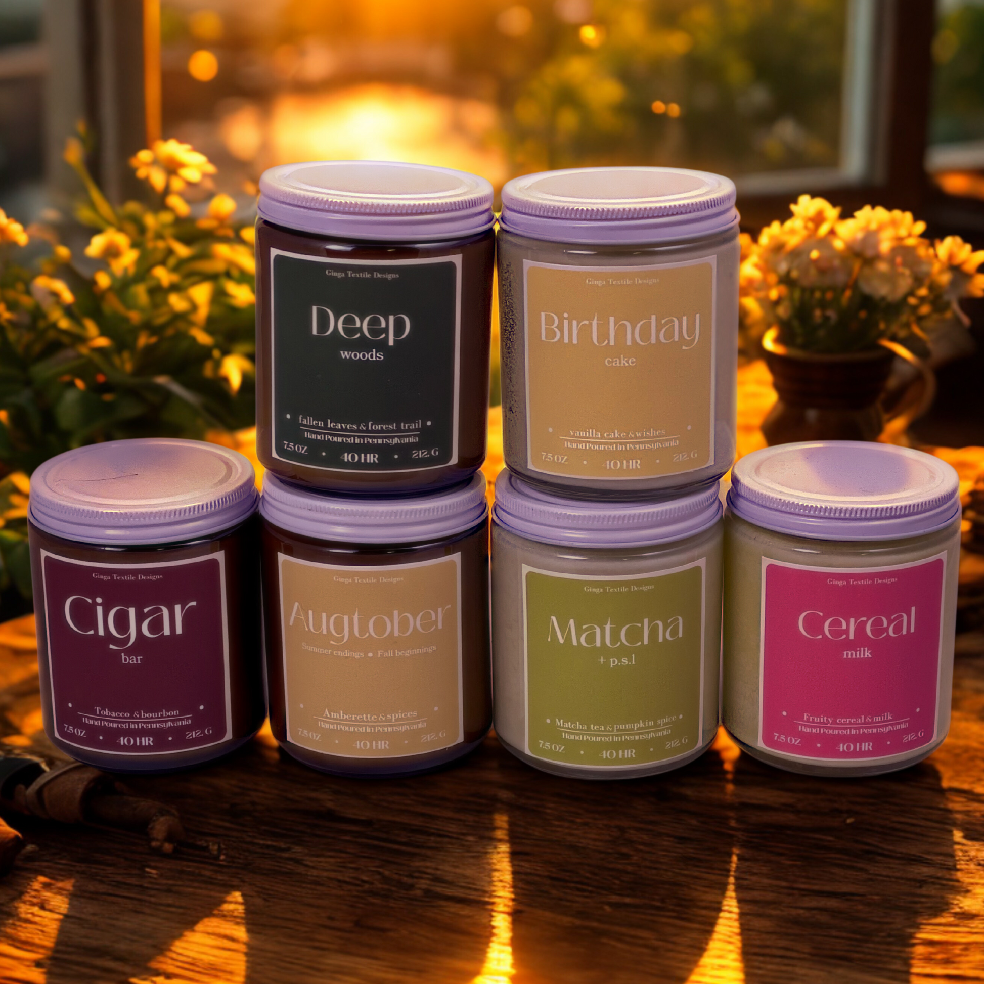 Set of candles with labels on a wooden surface with a sunset and flowers in vases in background