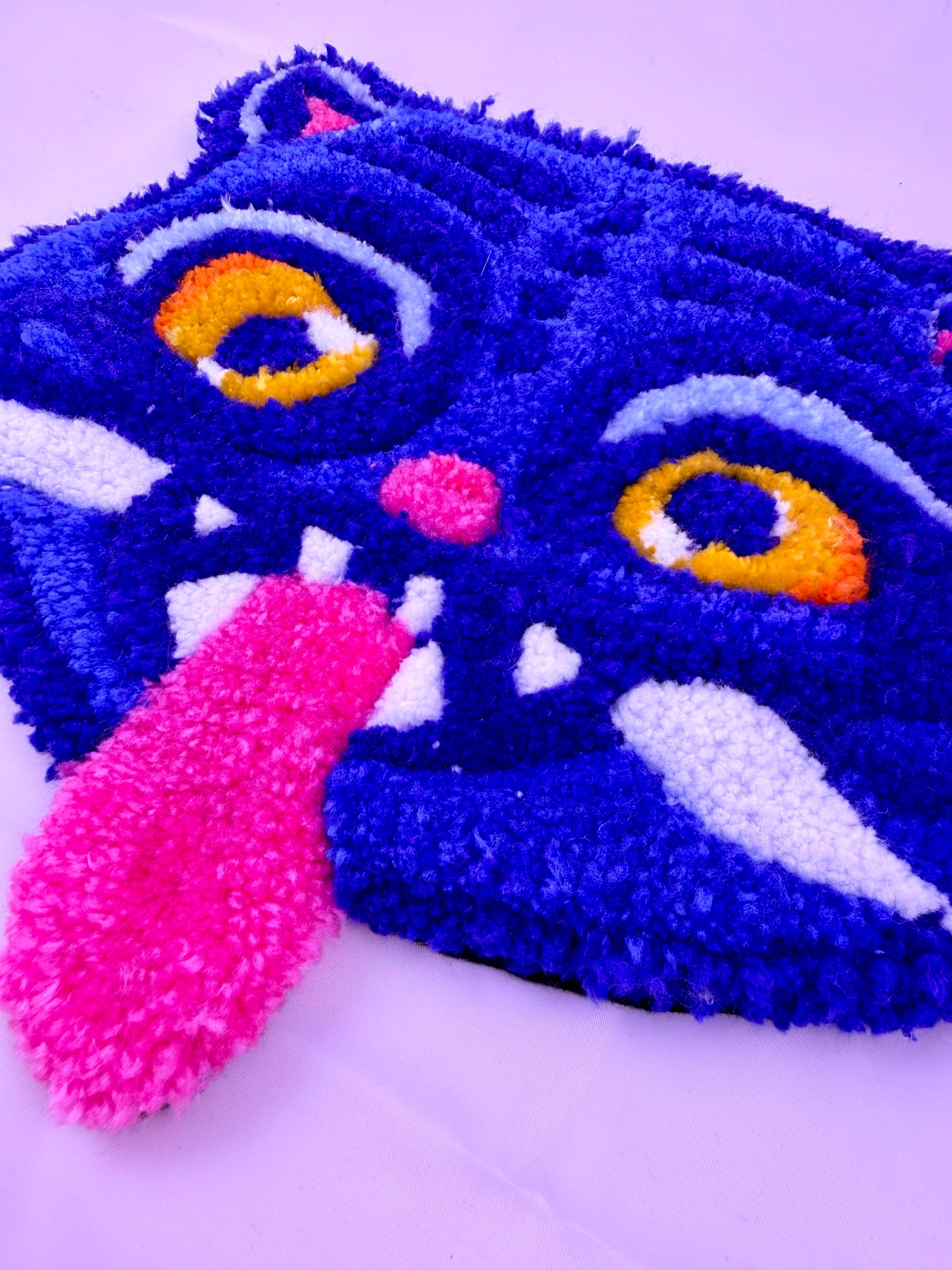Blue tufted rug with a pink tongue on a white background