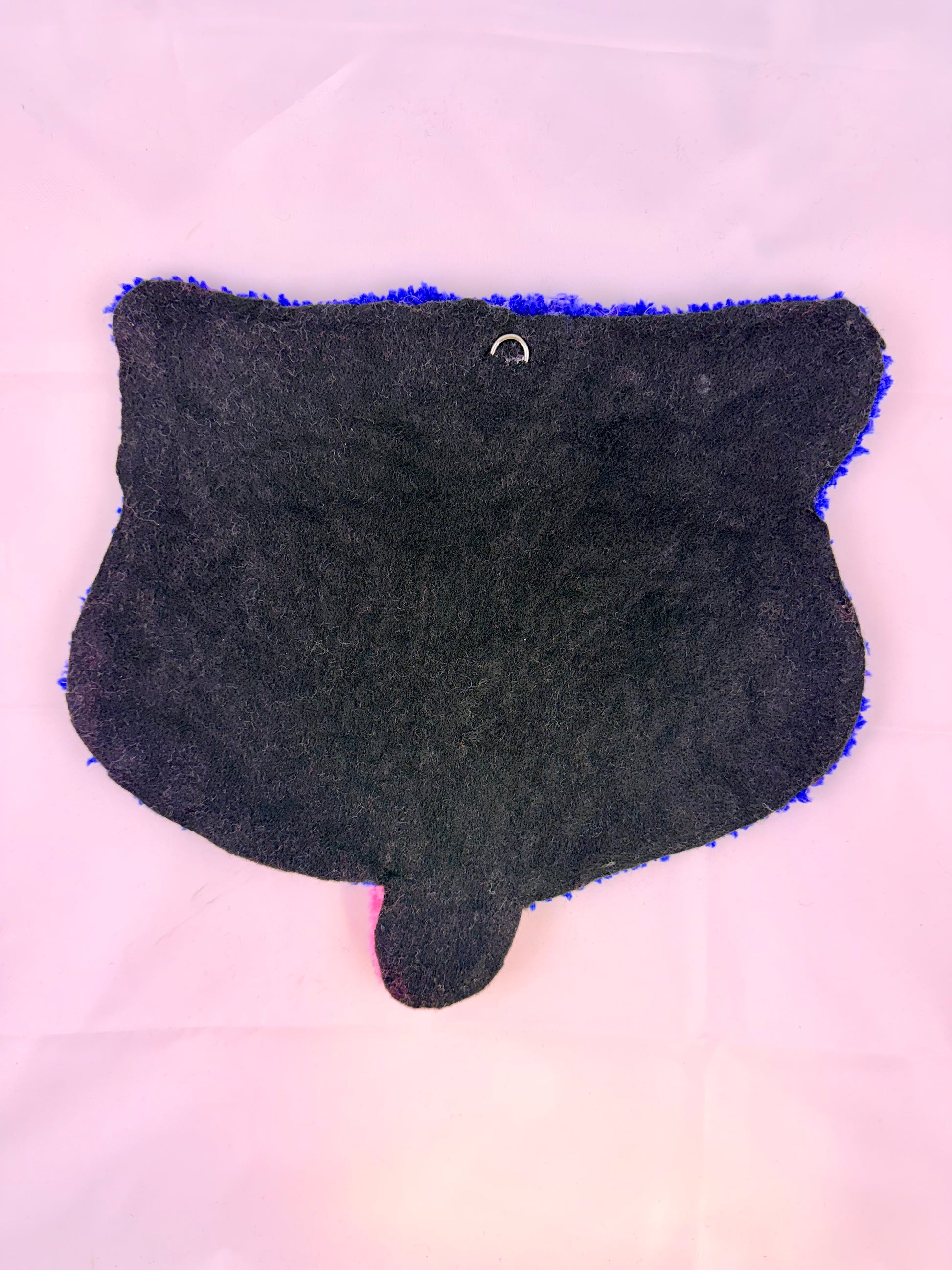 Black tufted rug with blue trim on a light pink background