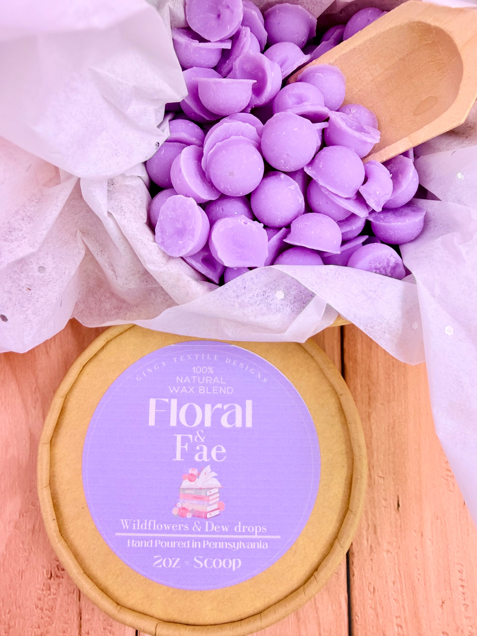 container of 'Floral Fae' wax melts with a wooden scoop on a wooden surface.