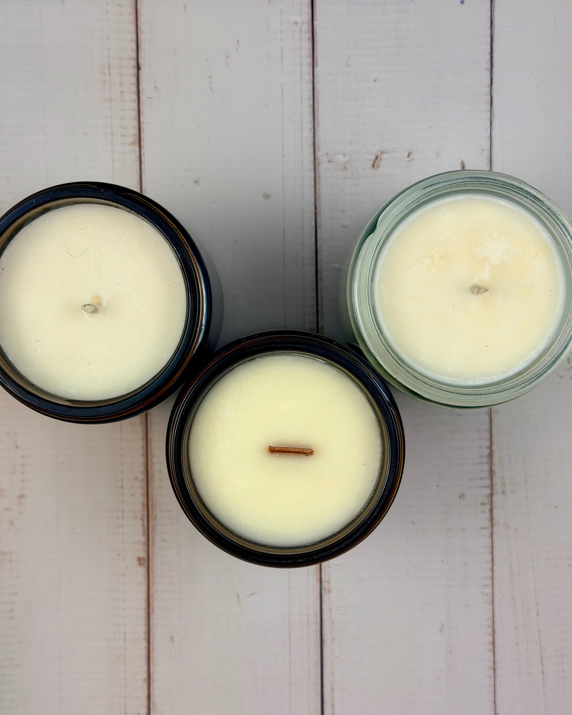 Three candles in glass jars on a wooden surface