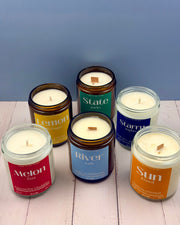 Set of candles in glass jars with labels on a wooden surface