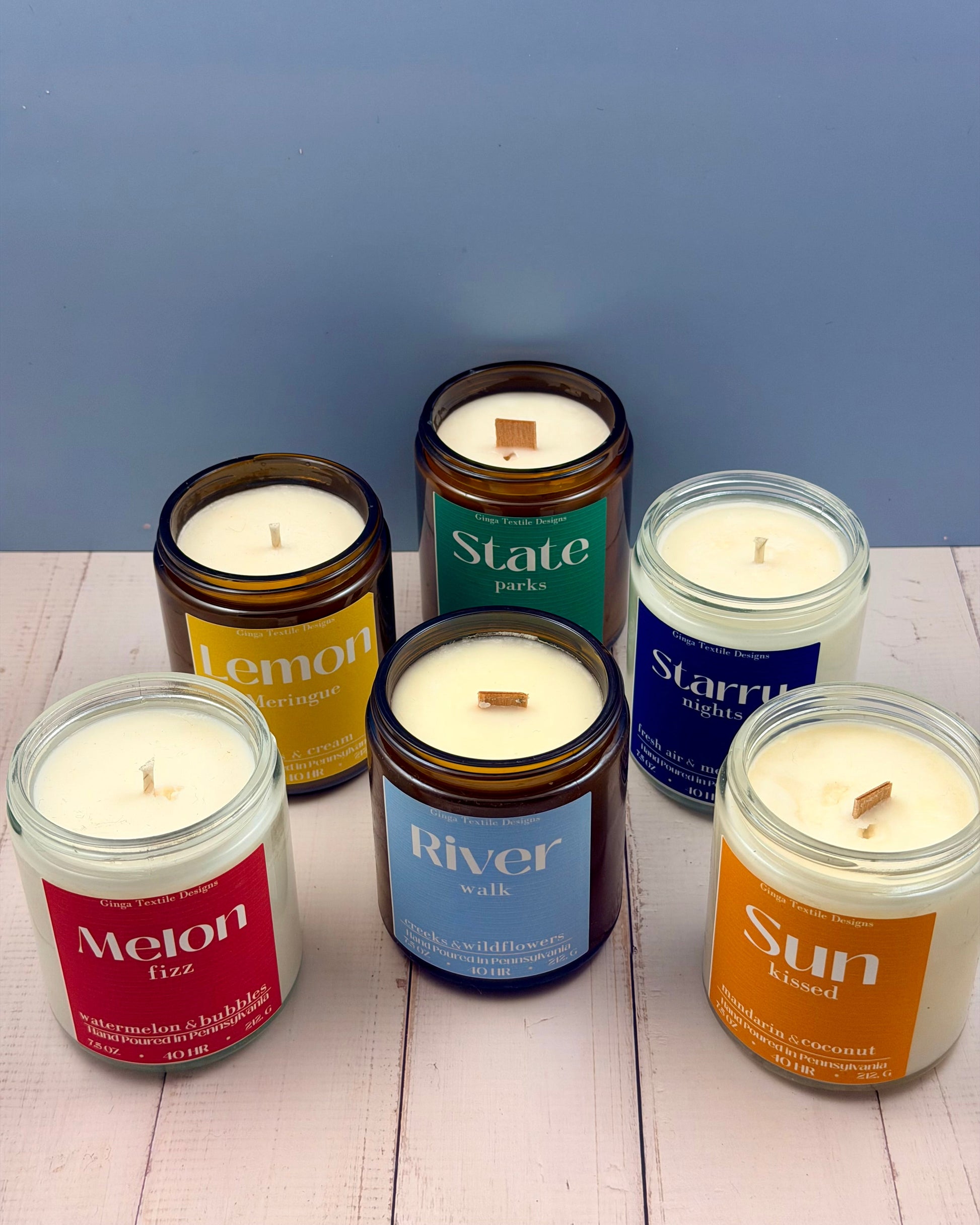 Set of candles in glass jars with labels on a wooden surface