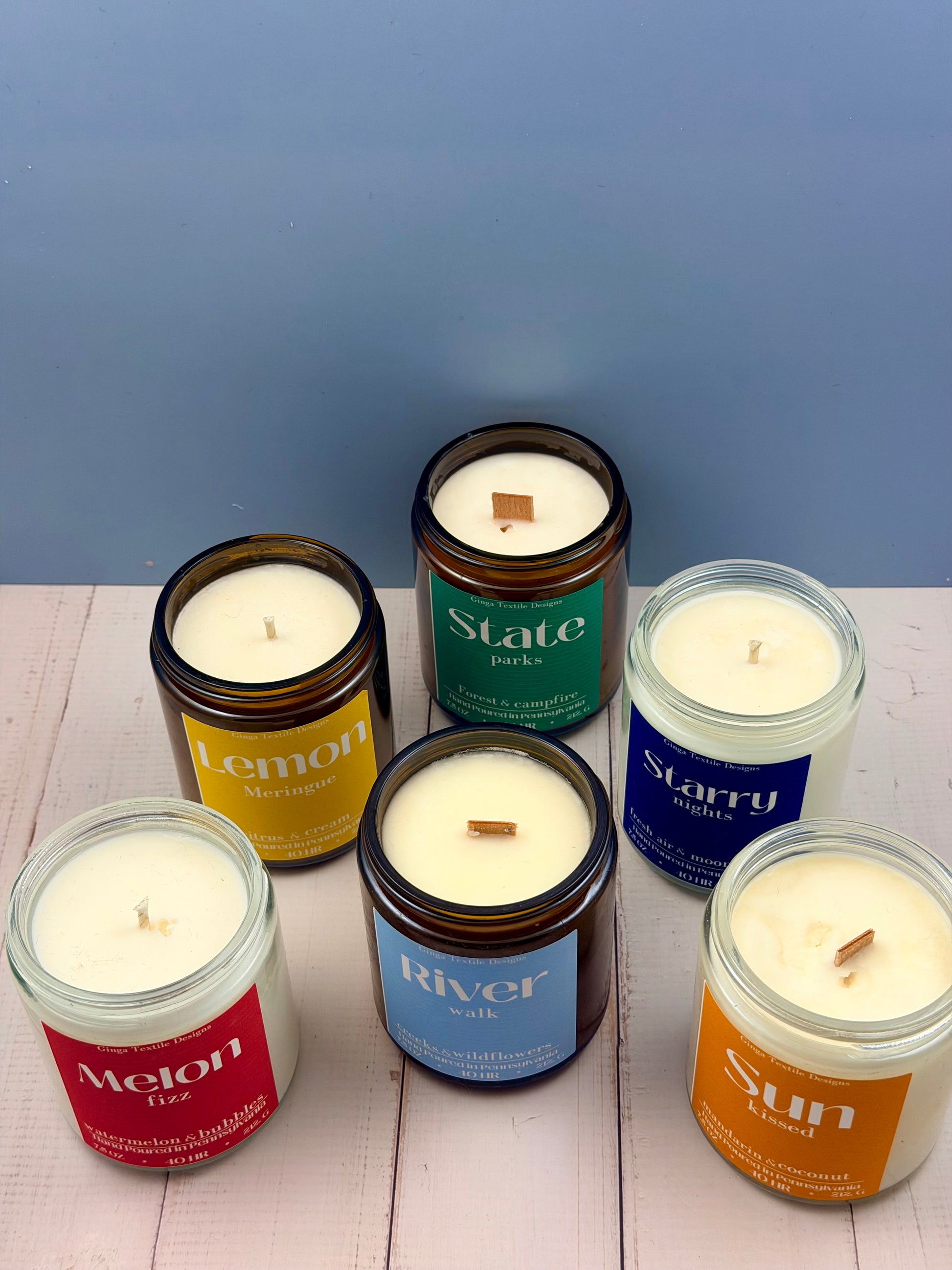 Set of candles with labeled lids on a wooden surface against a blue background