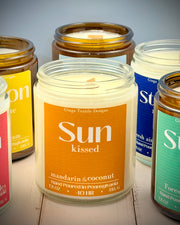 Collection of scented candles with visible labels on a wooden surface.