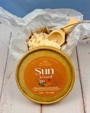 Sun kissed wax melt with a wooden scoop on a white surface
