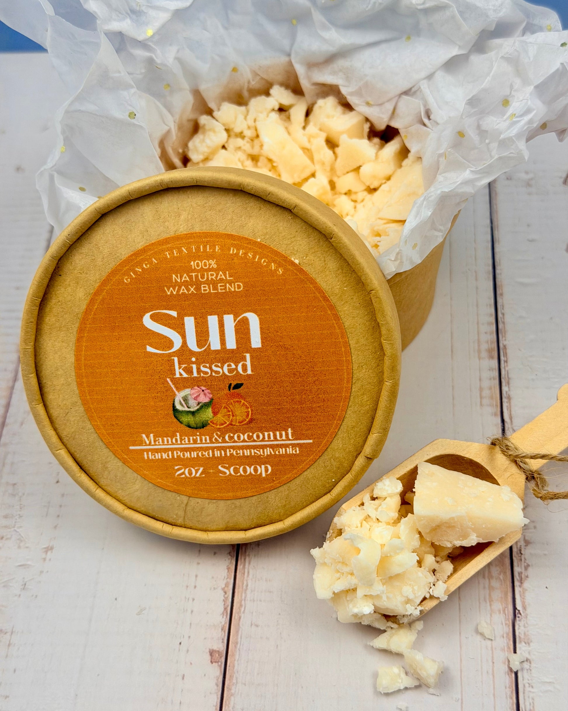 Sun Kissed wax melt container with a scoop on a wooden surface