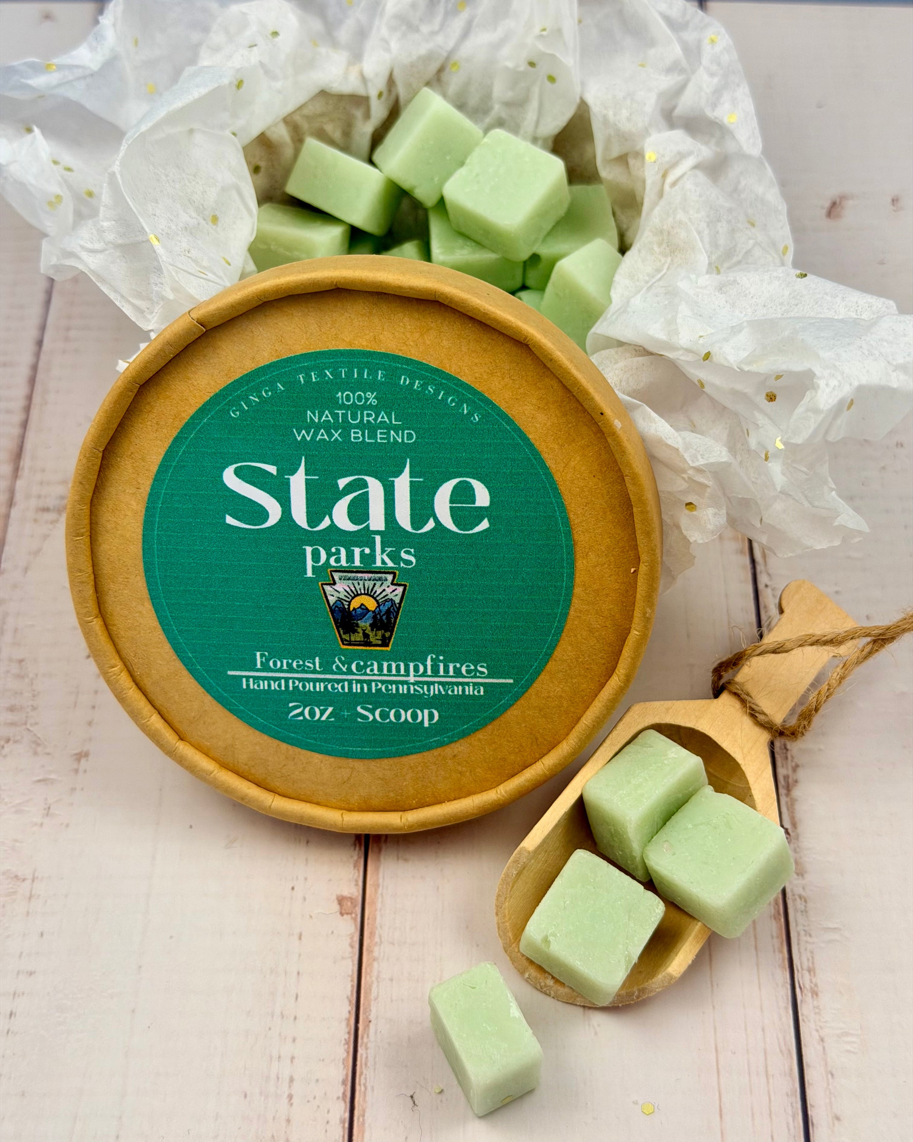 Wax melts in a container labeled 'State Parks' on a light wooden surface.