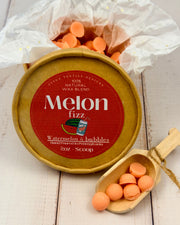 Melon fizz product with packaging and scoop on a wooden surface