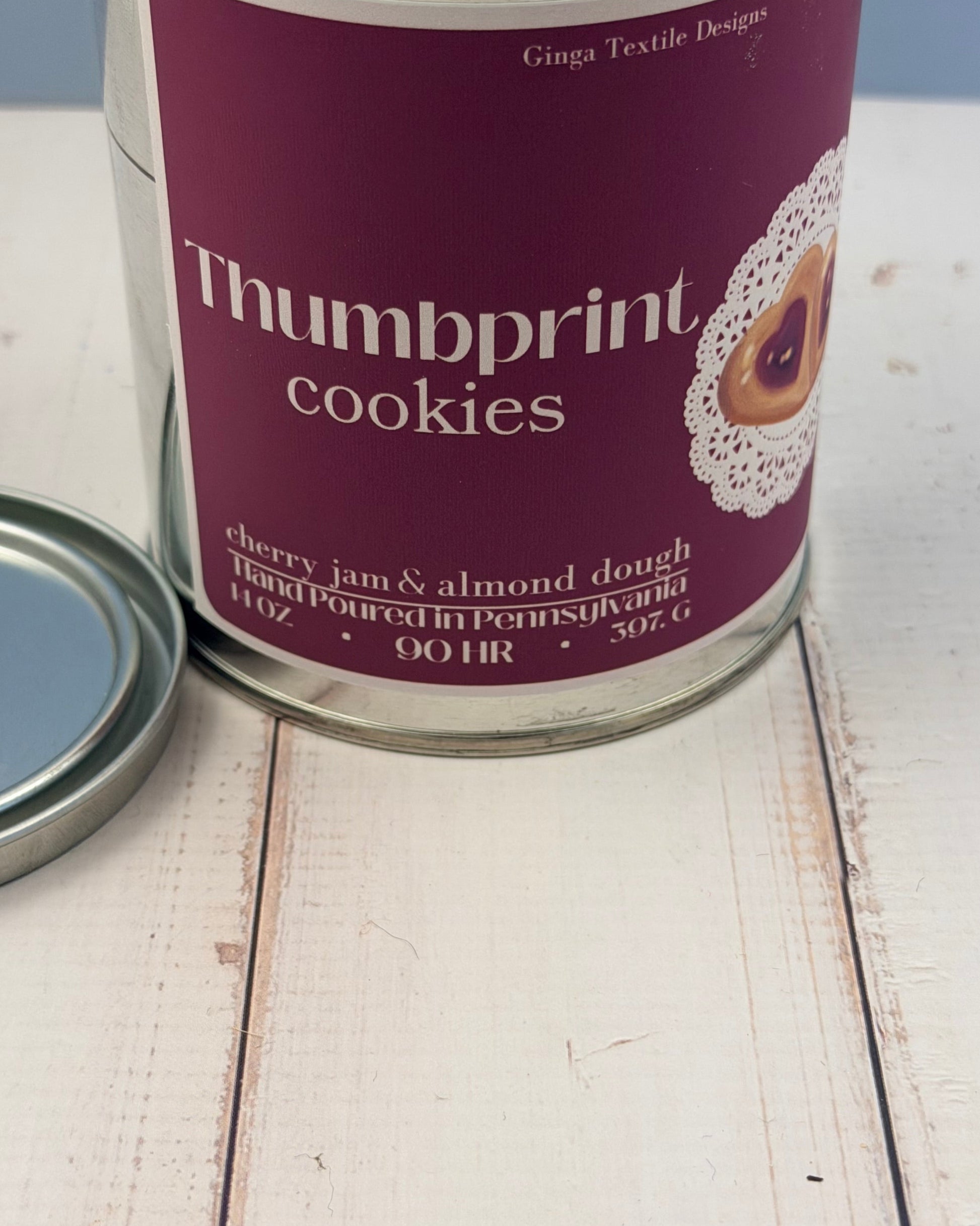 Can of Thumbprint Cookies scented candle in a tin on a wooden surface