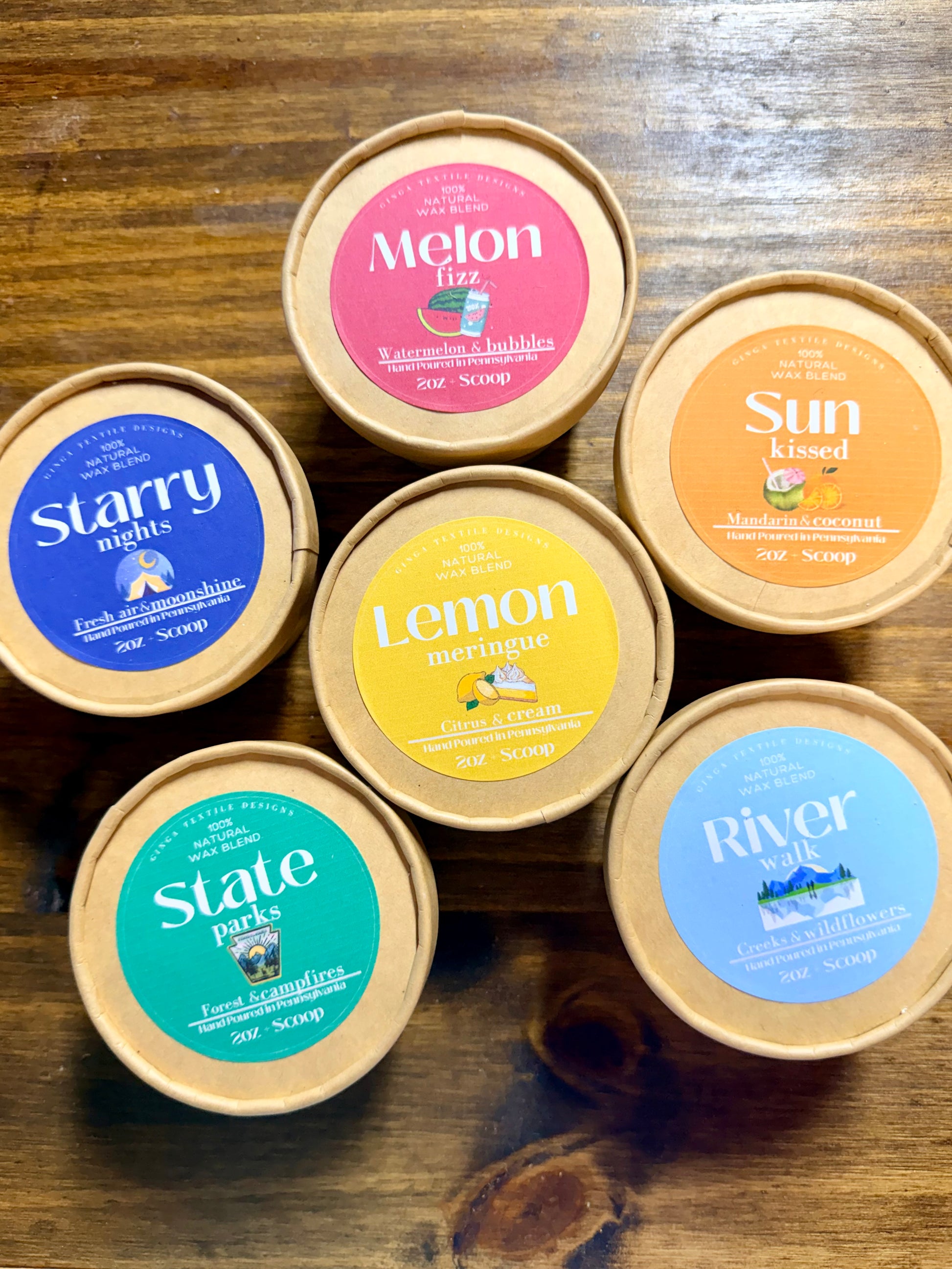 Assorted containers of wax melts with colorful labels on a wooden surface