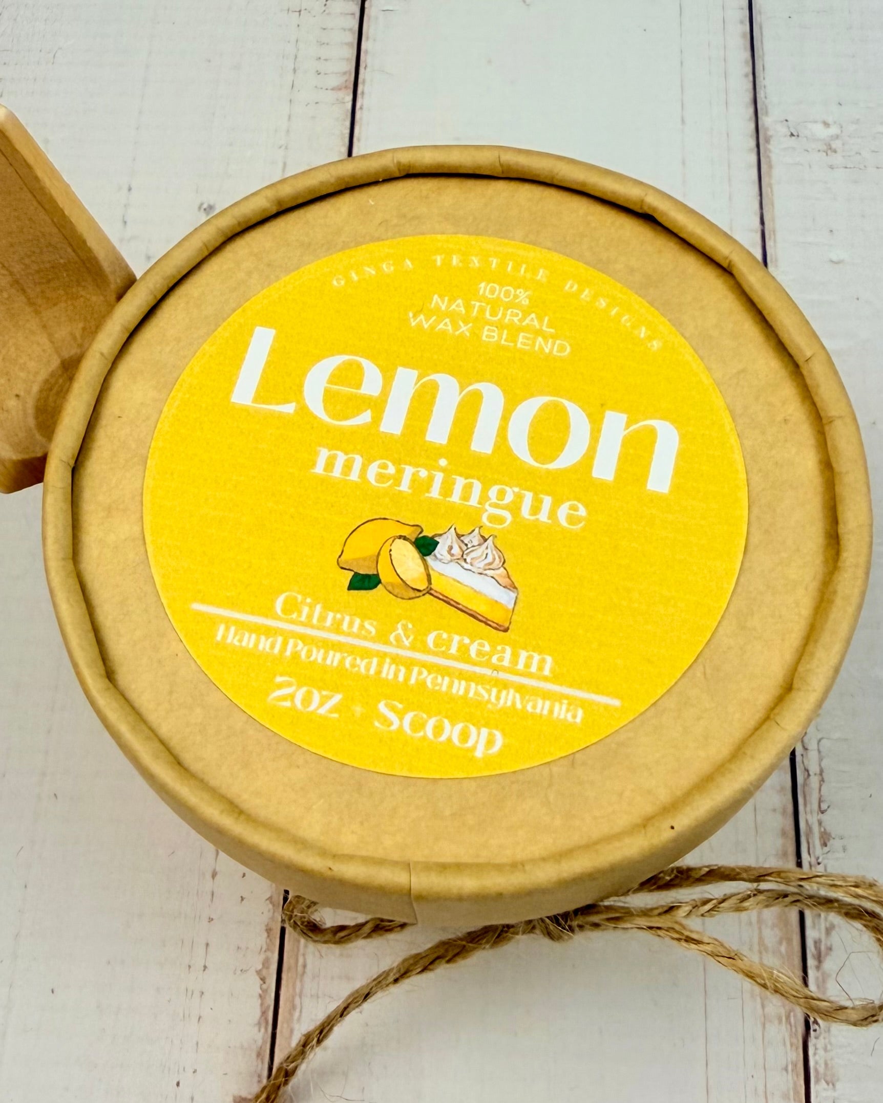 Jar of lemon meringue wax melts with a yellow label on a wooden surface