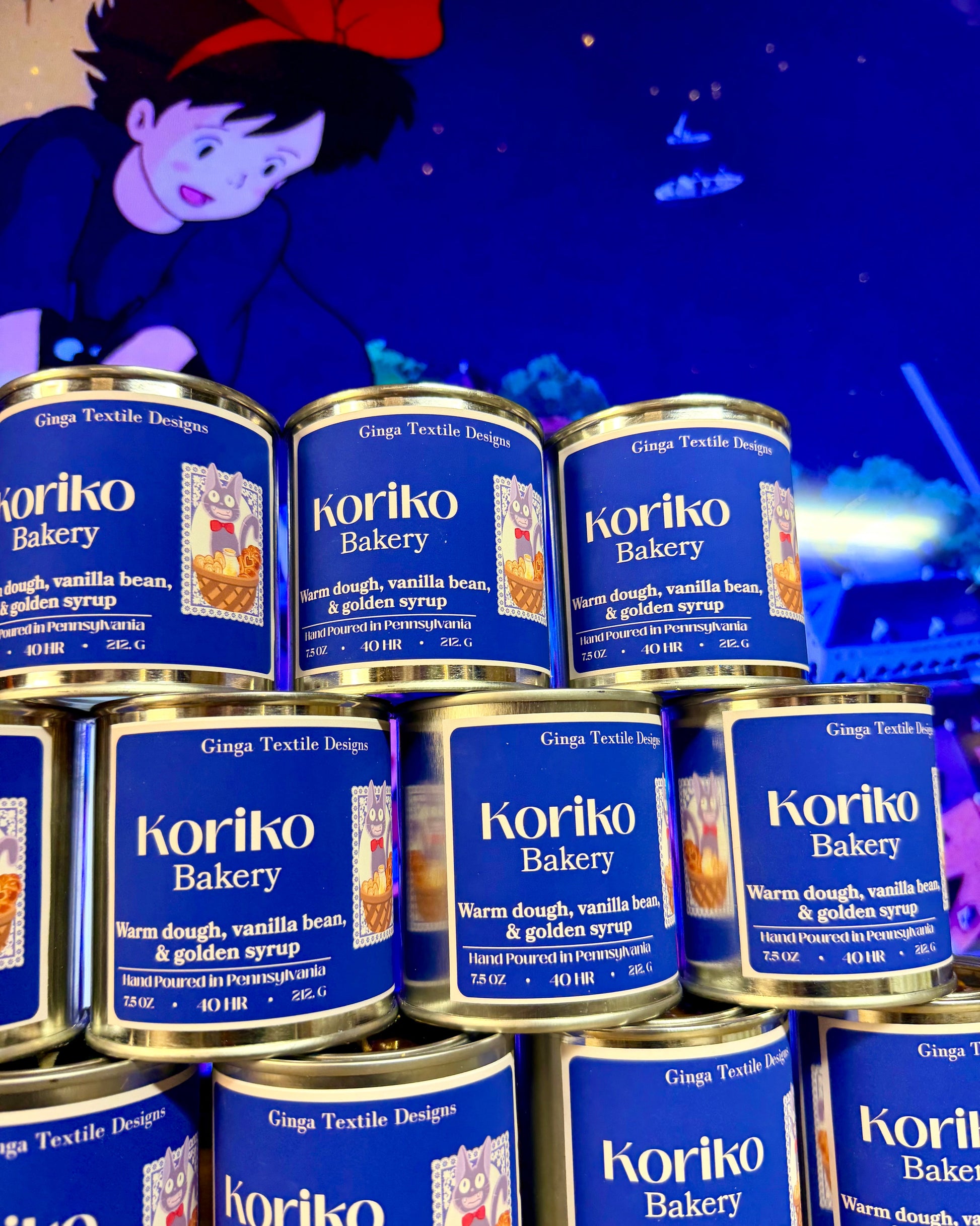 Multiple cans of Koriko Bakery on a blue background with a character in the corner.