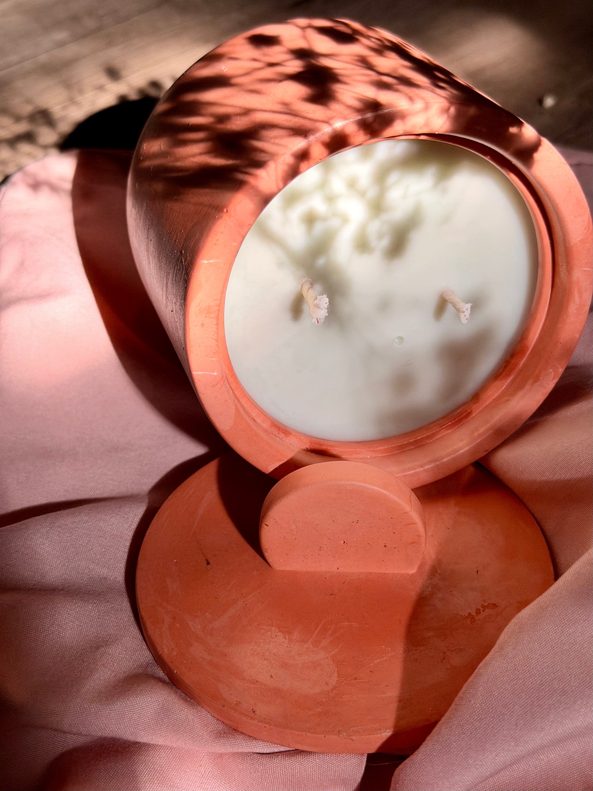 Cement candle with a light green wax inside on a pink fabric background