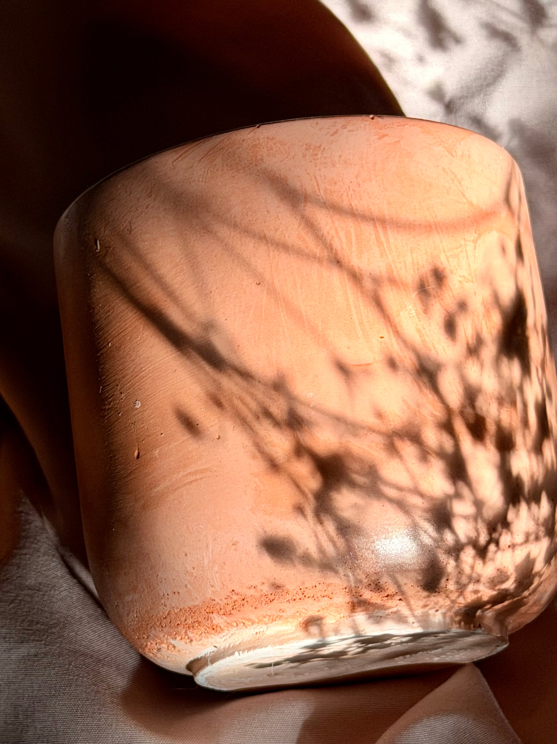 Close-up of a ceramic pot with a textured surface on a soft fabric background