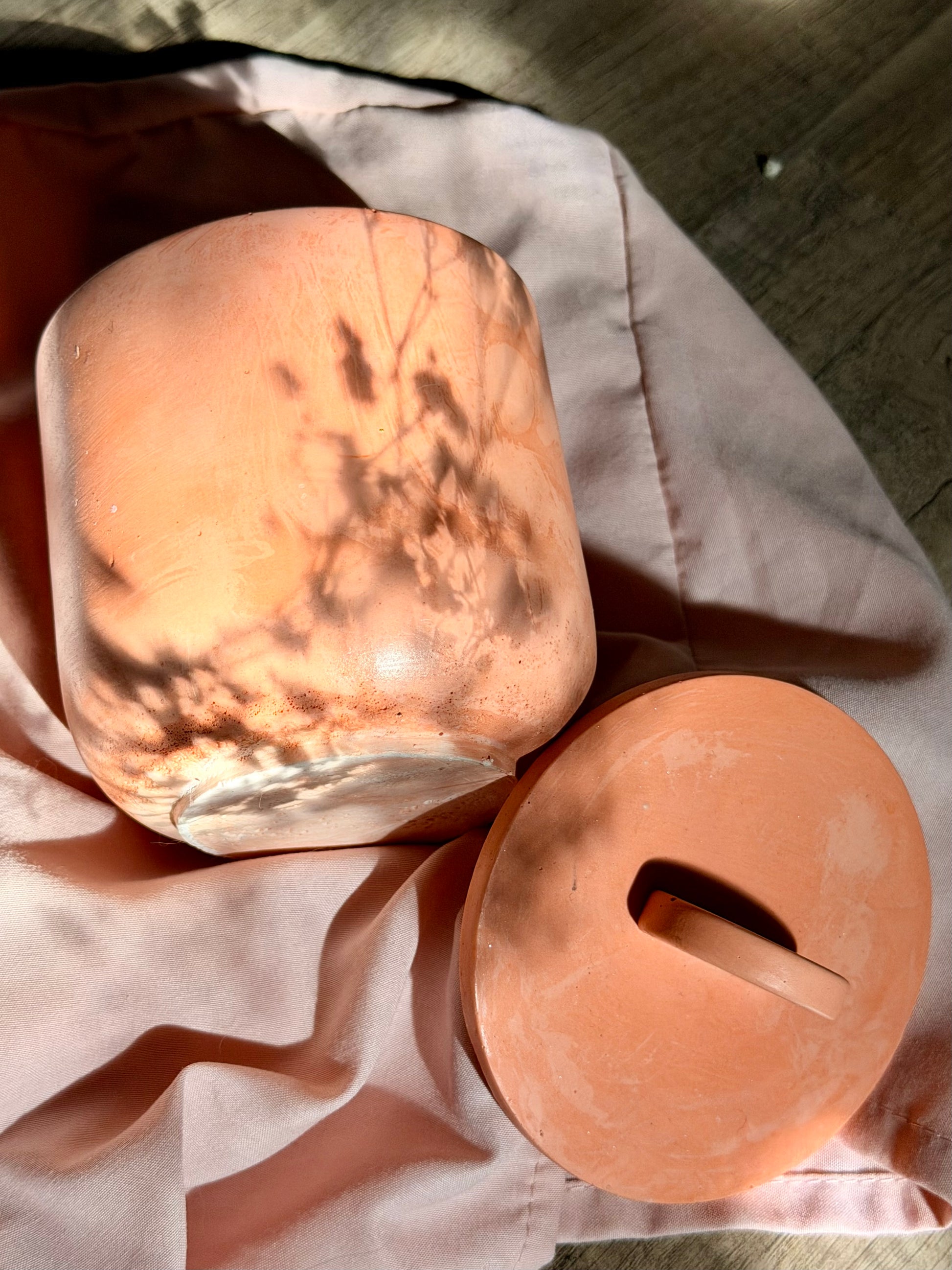 Two stone-like containers on a fabric surface