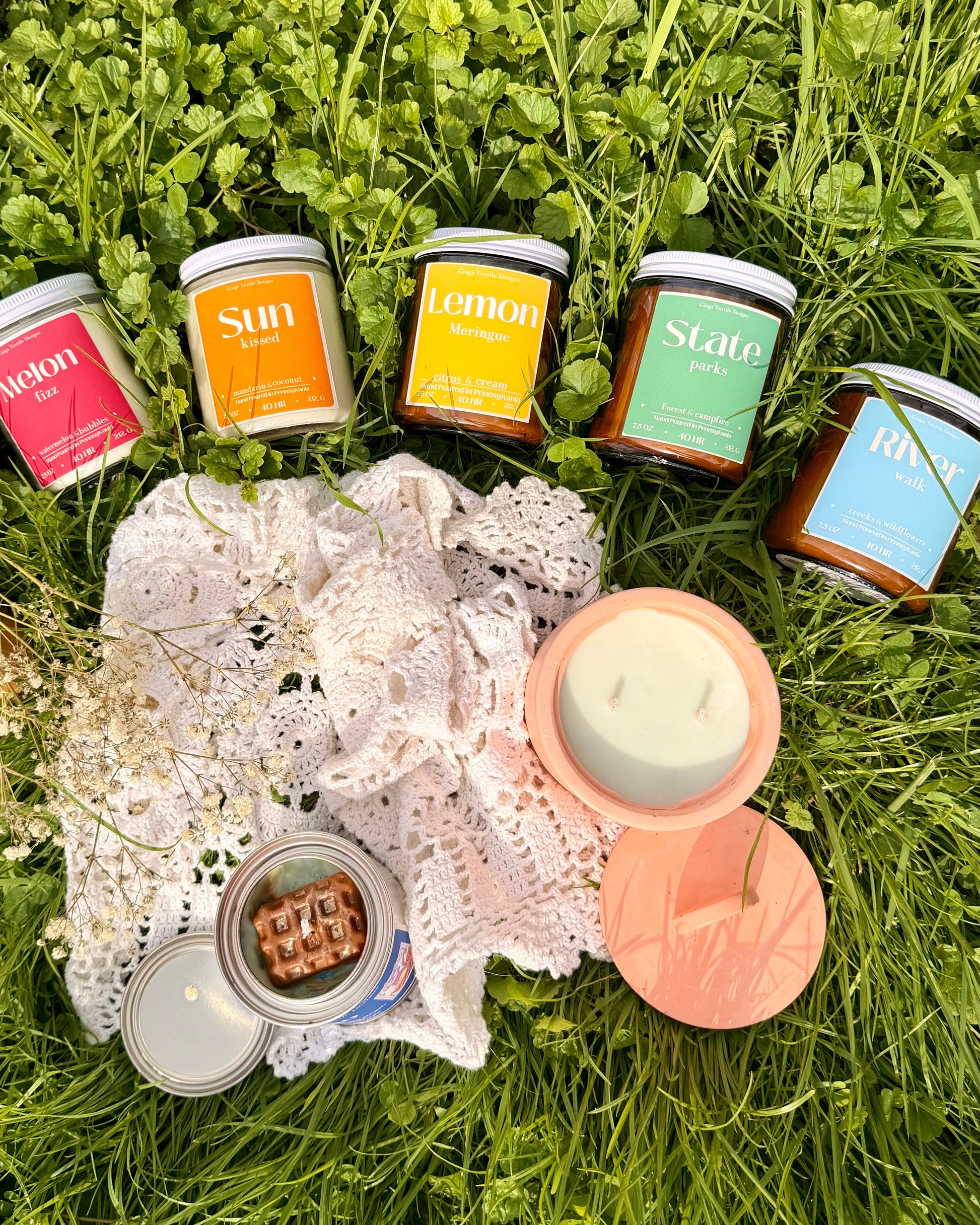 Assorted candles on a lace doily with a heart shape in the grass