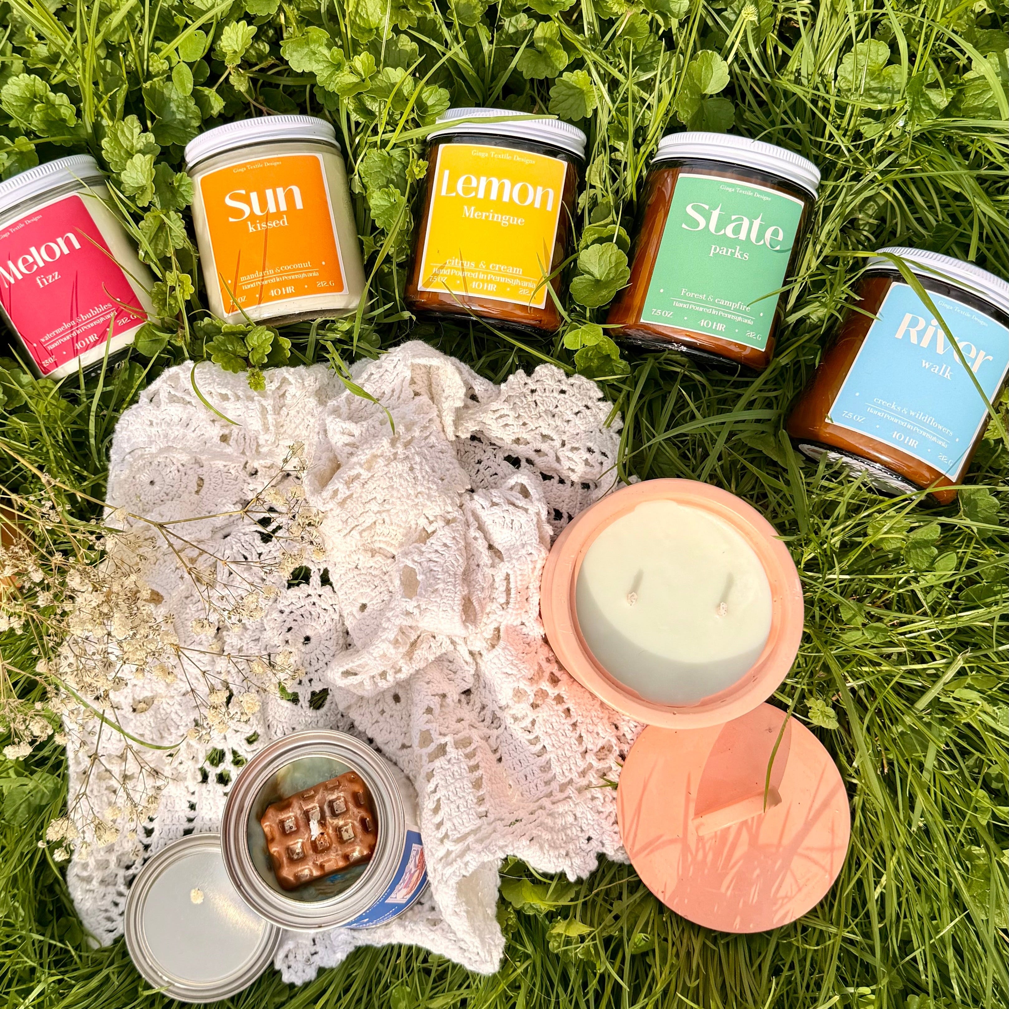 Assorted candles on a lace doily with a heart shape in the grass
