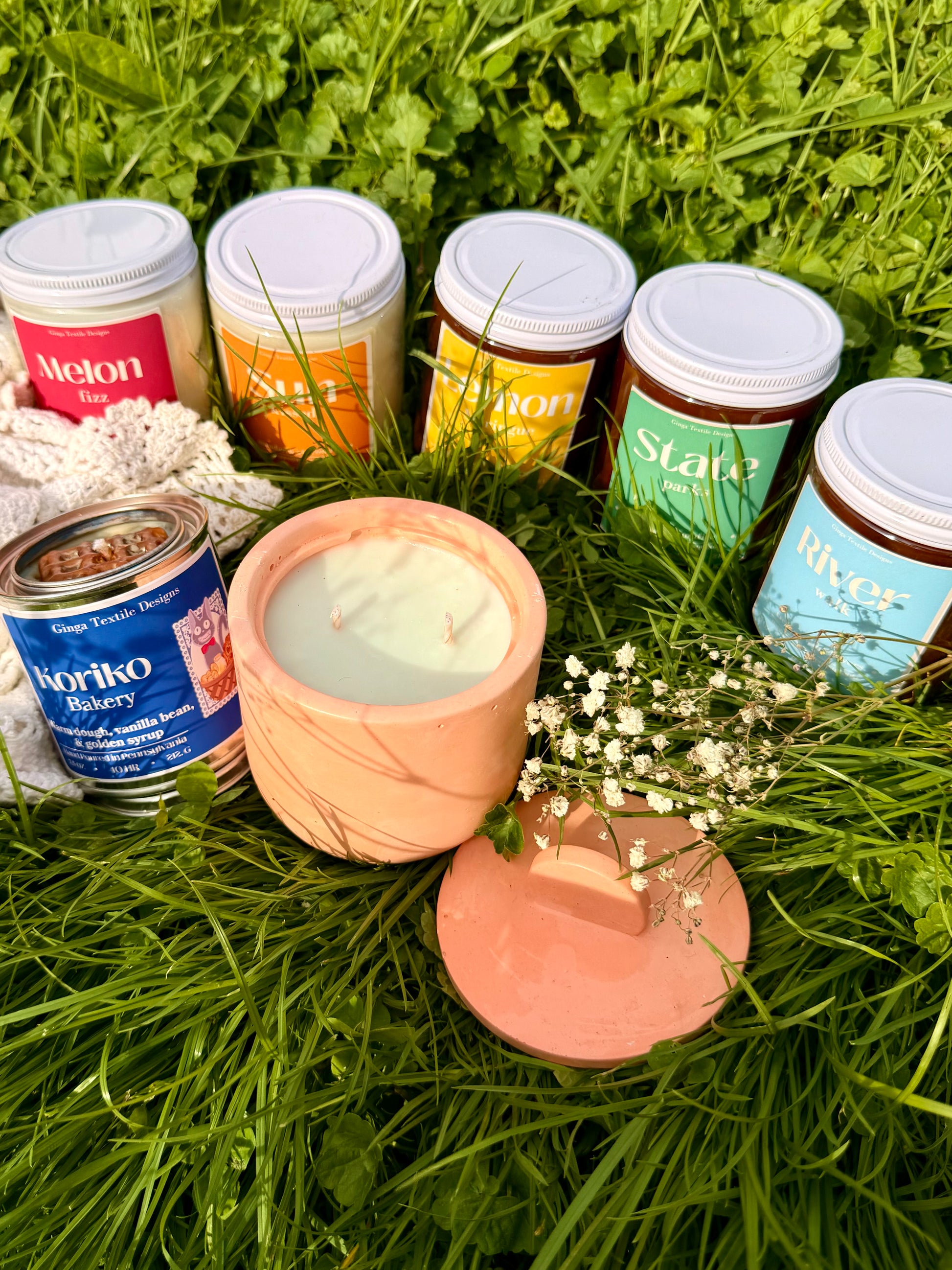 Collection of candles with labeled containers on grass