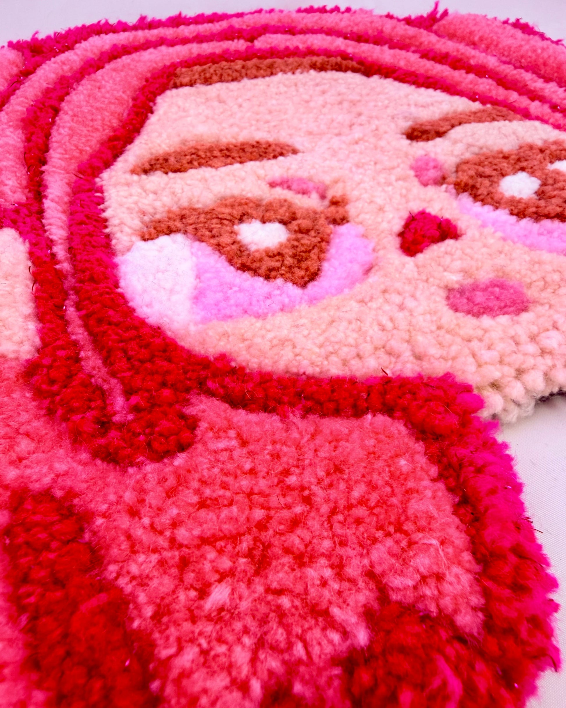Close-up of a pink and red textured rug with a cartoon character design.