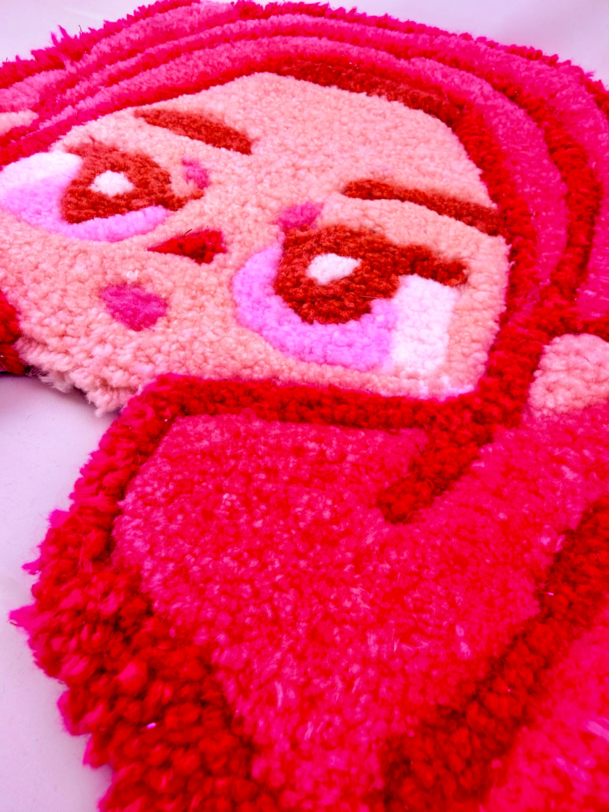 Close-up of a textured pink tufted rug of with a face design on a white background