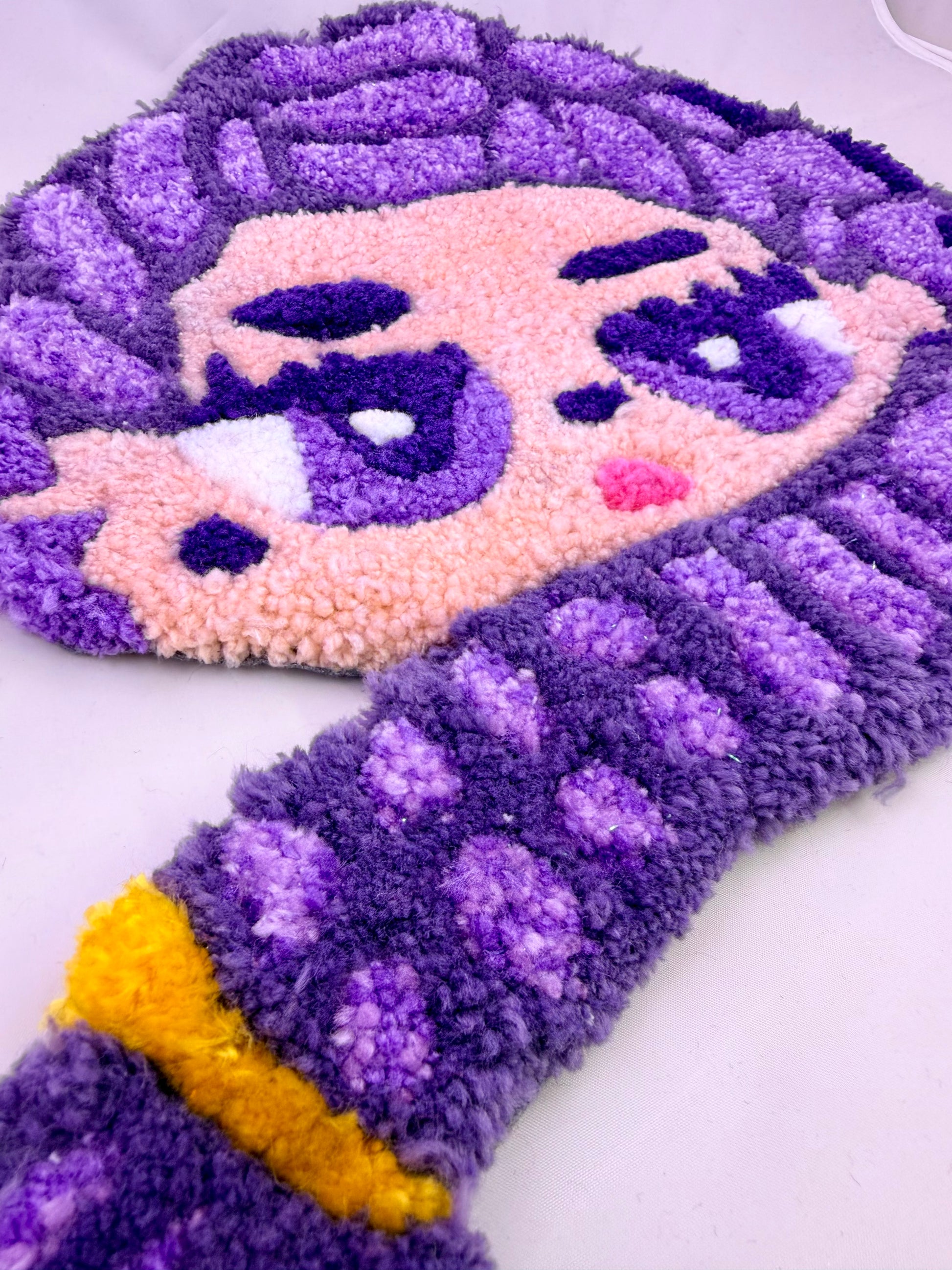 Purple and pink cartoon character rug on a white background