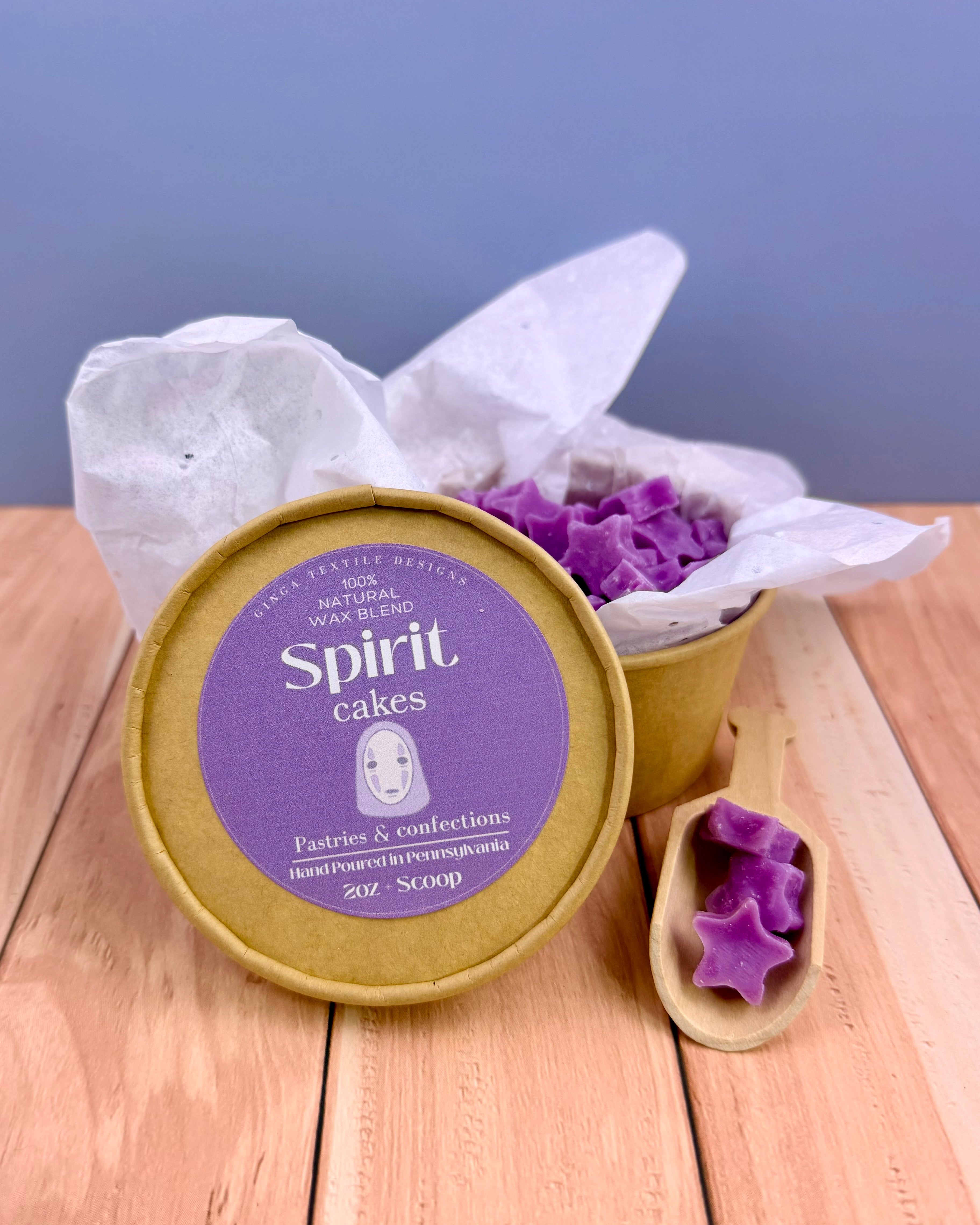 Container of purple star-shaped wax melts with a 'Spirit Cakes' label on a wooden surface.