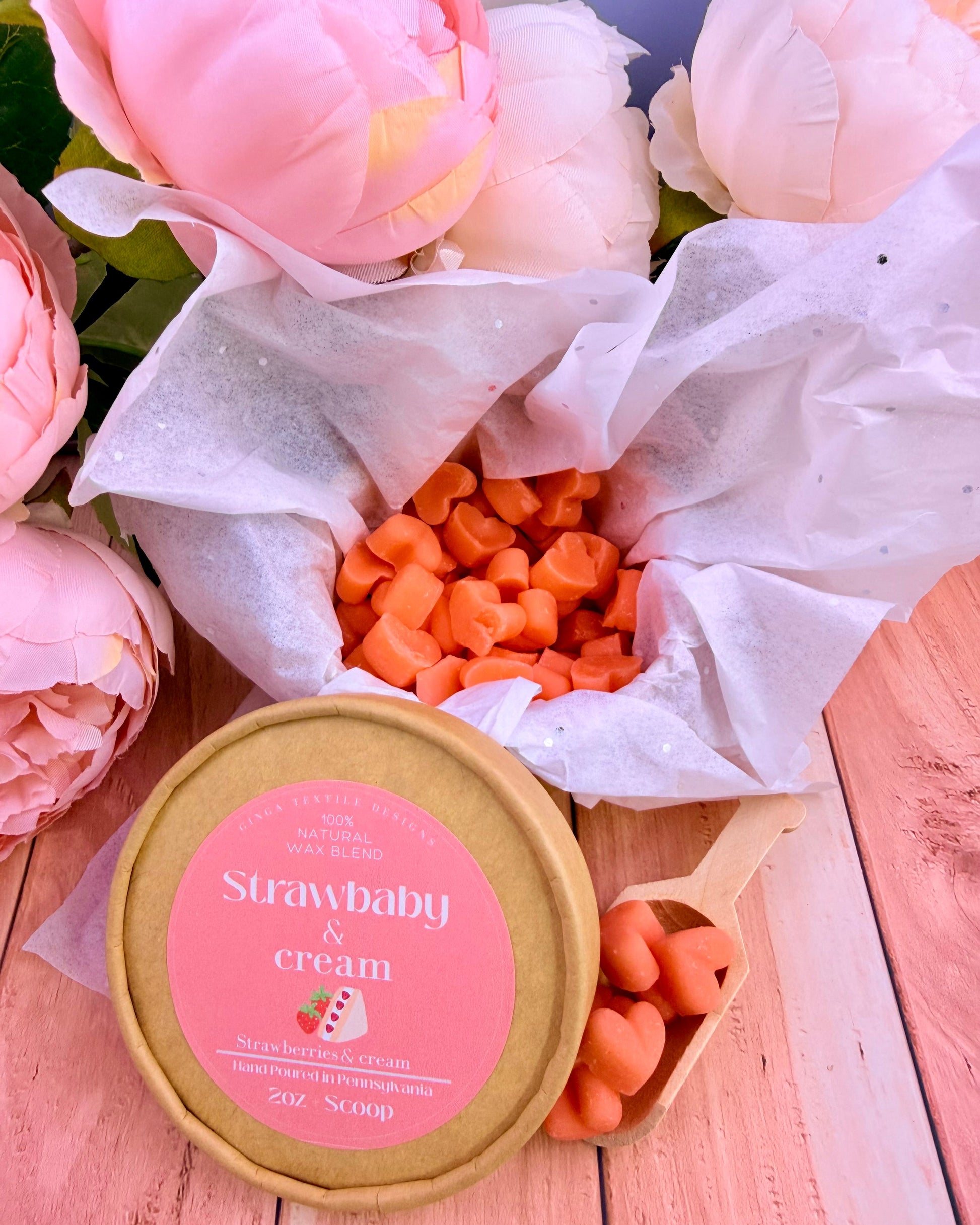 Bouquet of pink flowers with a container labeled 'Strawbaby & Cream' on a wooden surface.