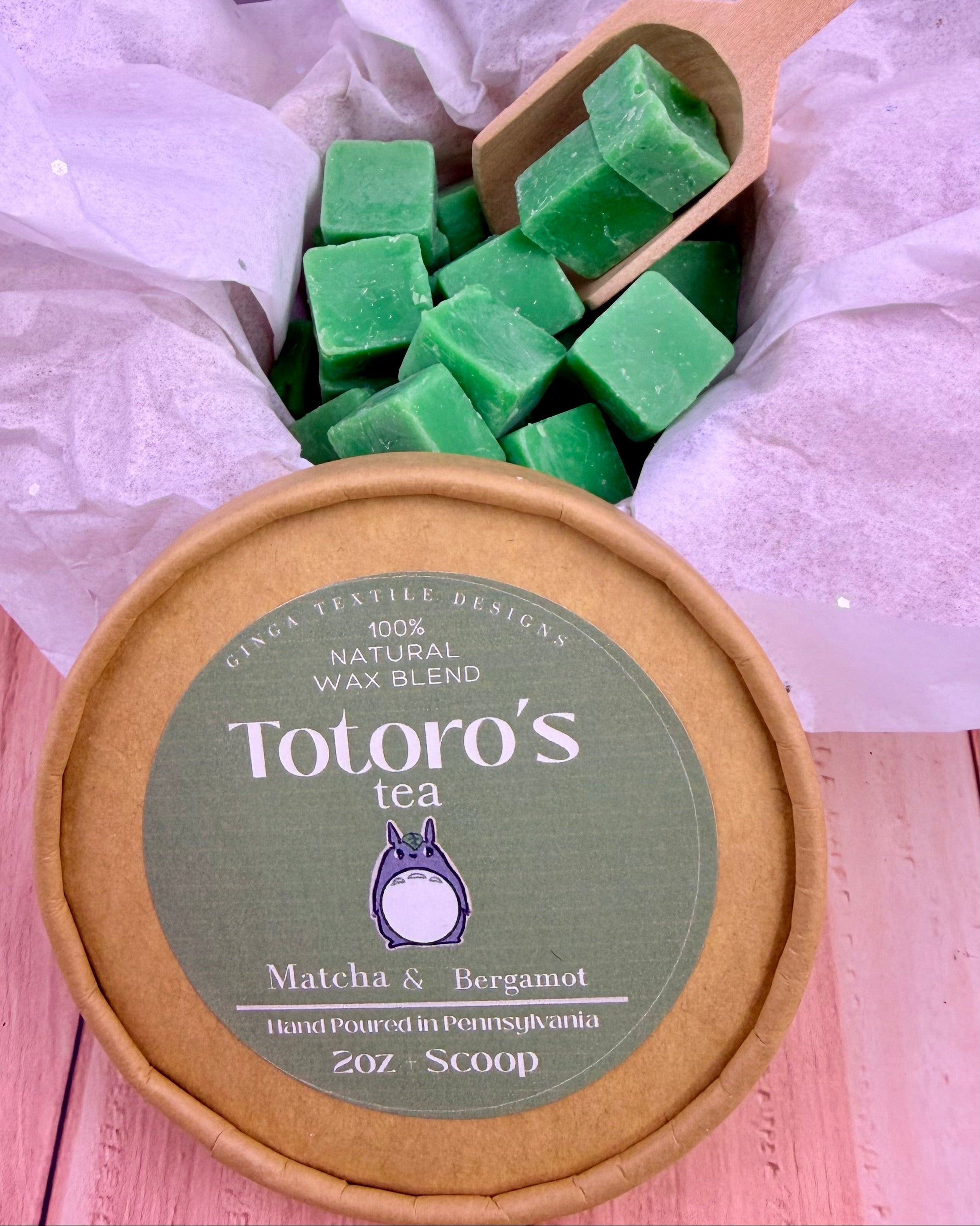 Totoro's Tea wax melts with a wooden scoop on a light pink background