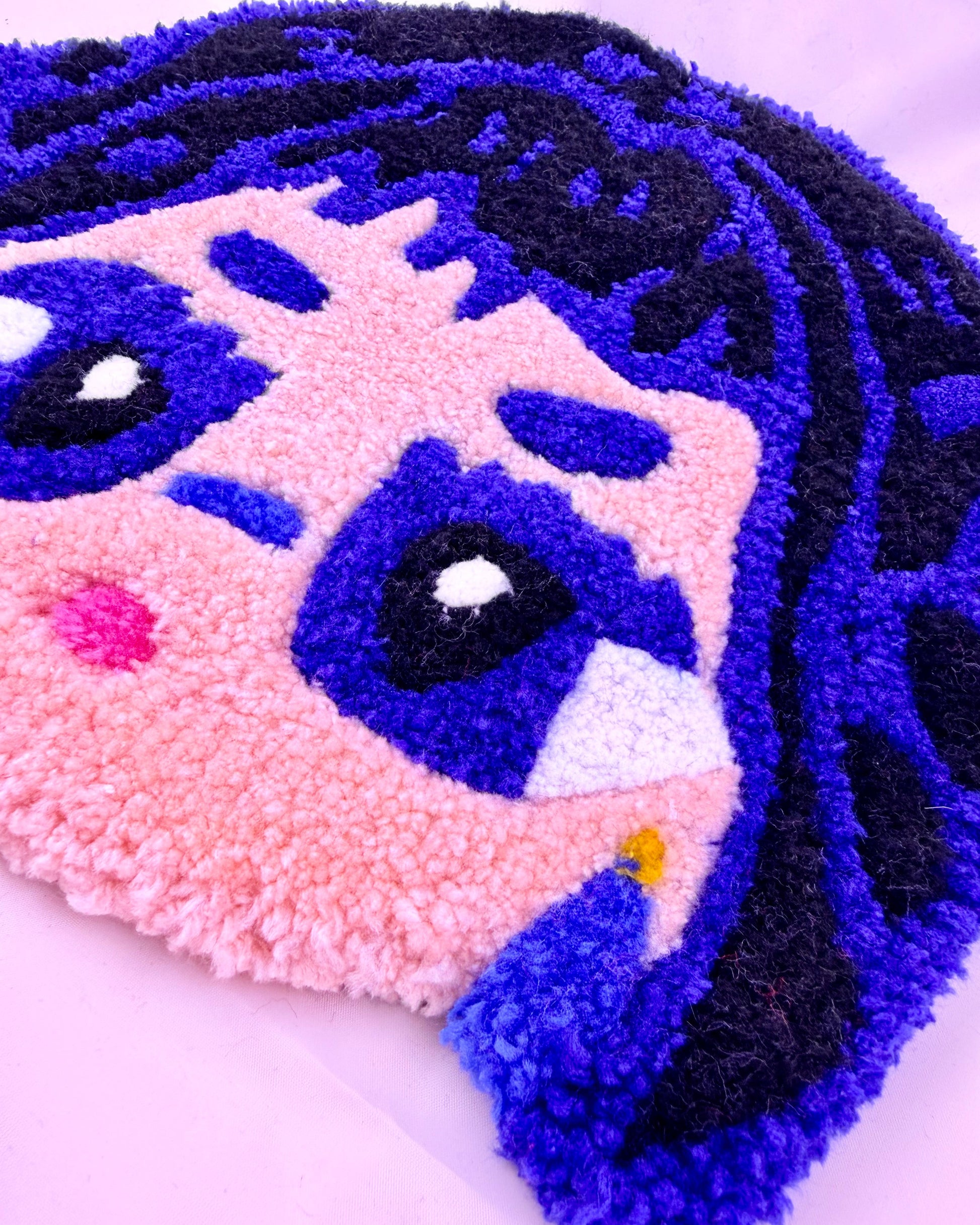 Close-up of a textured tufted rugwith a cartoon character face design on a white background