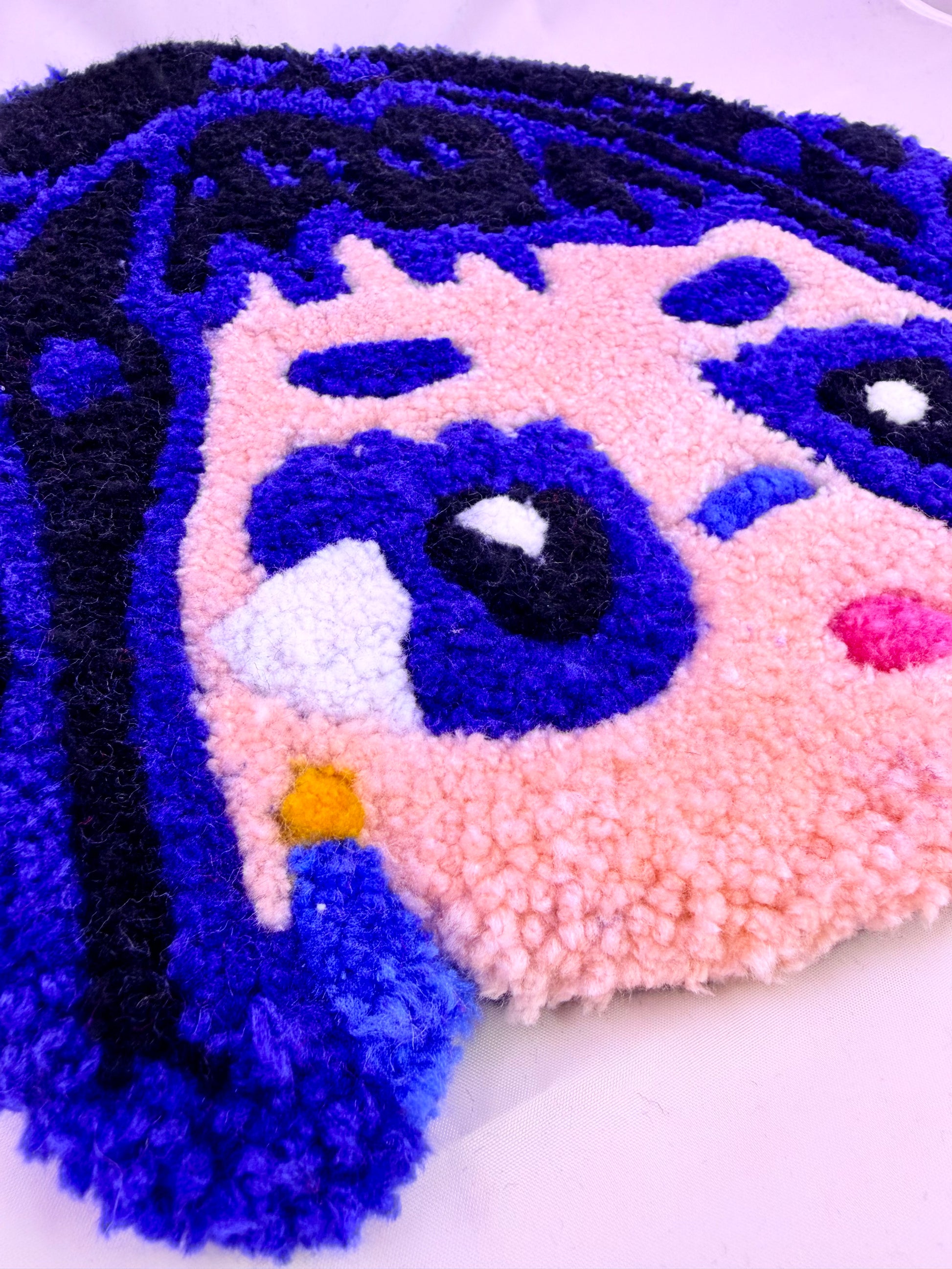 Close-up of a textured, colorful face design with blue hair on a white background