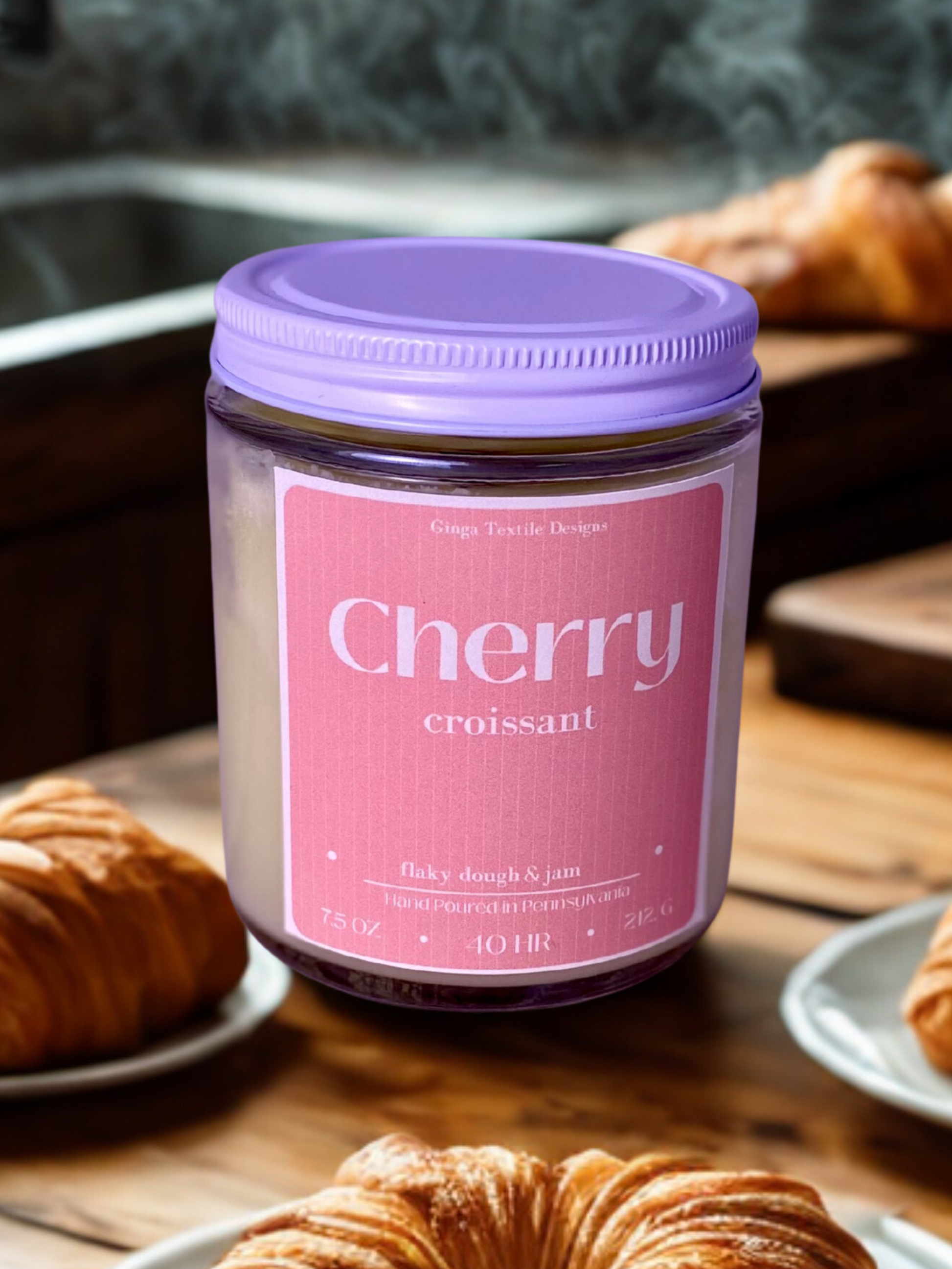 Jar of cherry croissant-scented candle on a table with pastries