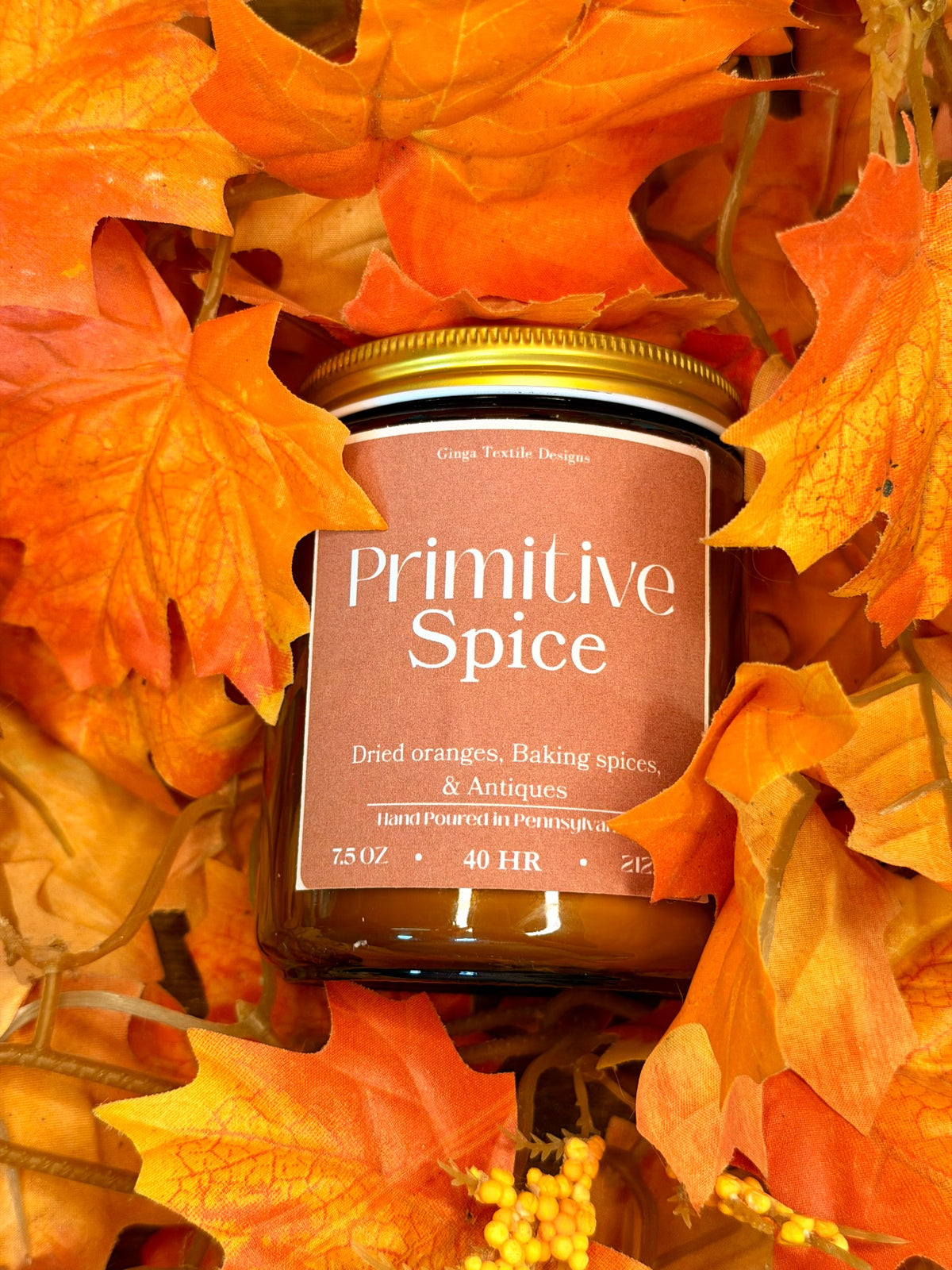 Primitive Spice 7.5 oz amber glass candle in autumn leaves
