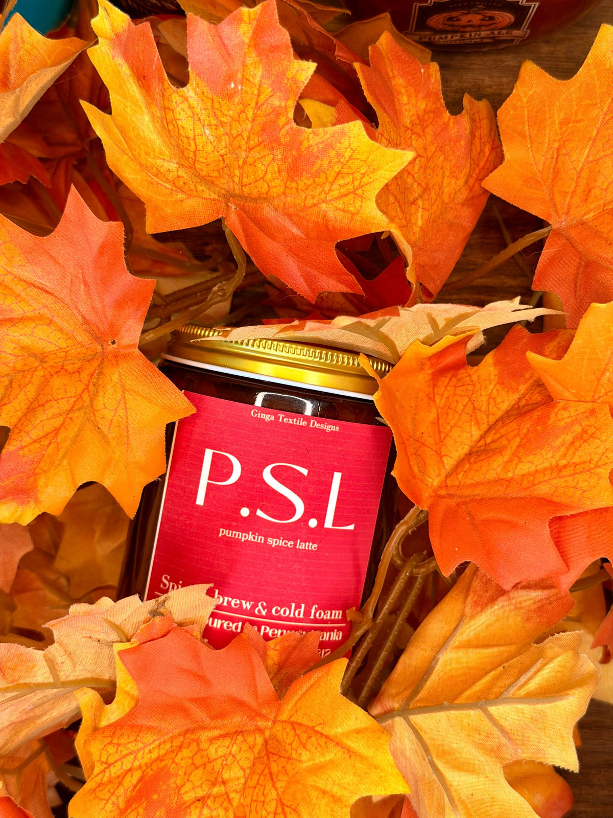 Pumpkin Spice Latte 7.5 oz amber glass candle styled with autumn leaves
